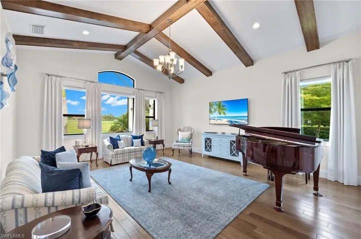 Family room with lofted ceiling with beams, plenty of natural light, and hardwood floors