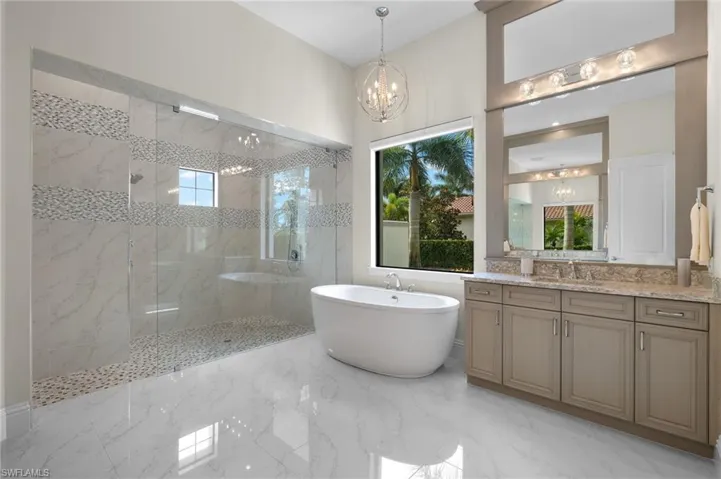 Bathroom featuring vanity, a notable chandelier, and plus walk in shower
