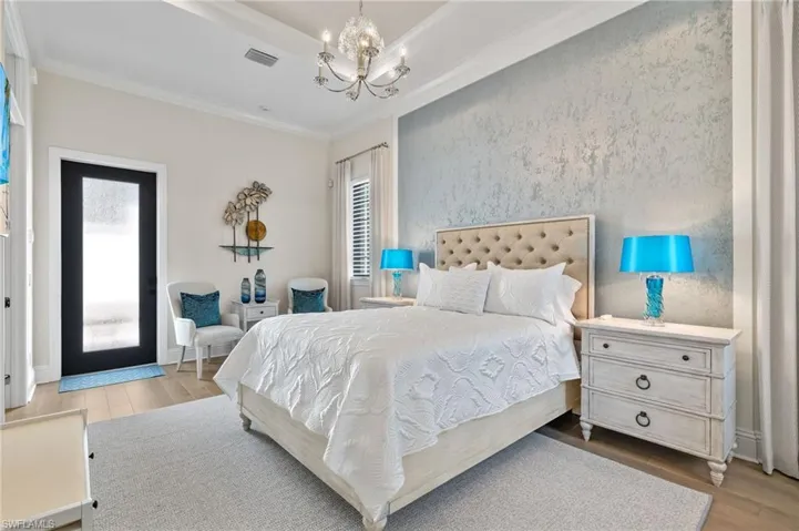 Bedroom with light hardwood style floors, ornamental molding, and a chandelier