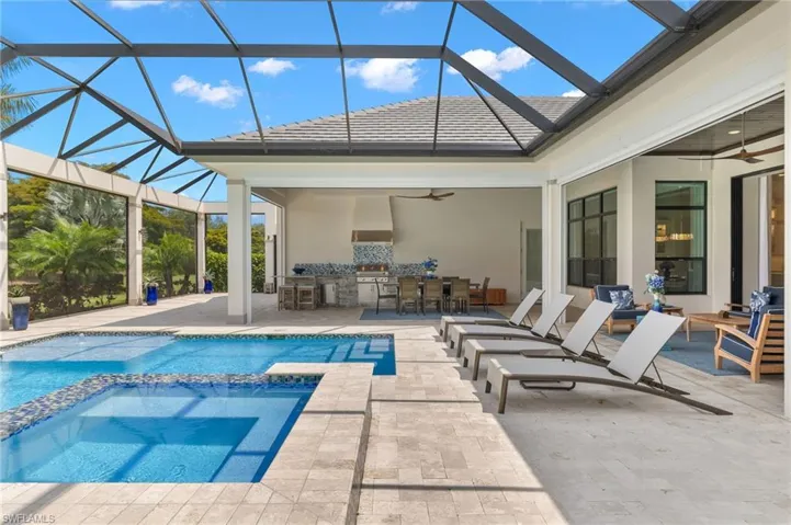 View of swimming pool with a patio, ceiling fan, a bar, and enclosure