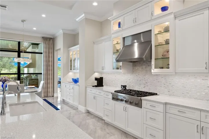 Kitchen featuring white cabinets, range hood, and stainless steel gas cooktop