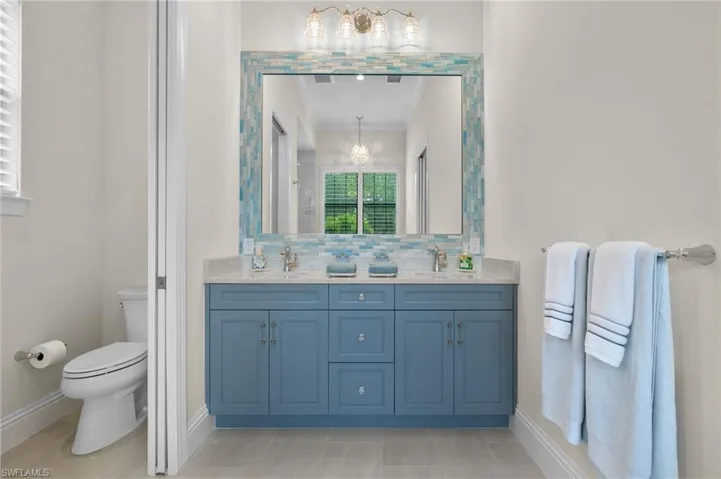 Bathroom with an inviting chandelier, vanity, backsplash, and toilet