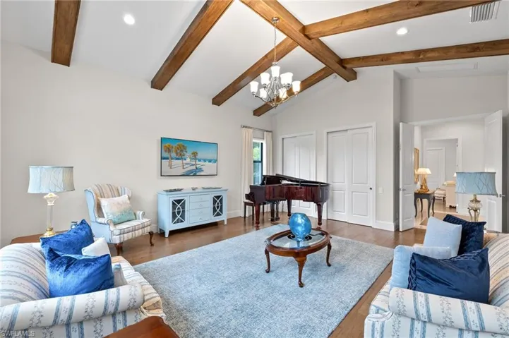 Family room with hardwood flooring, lofted ceiling with beams, and a chandelier