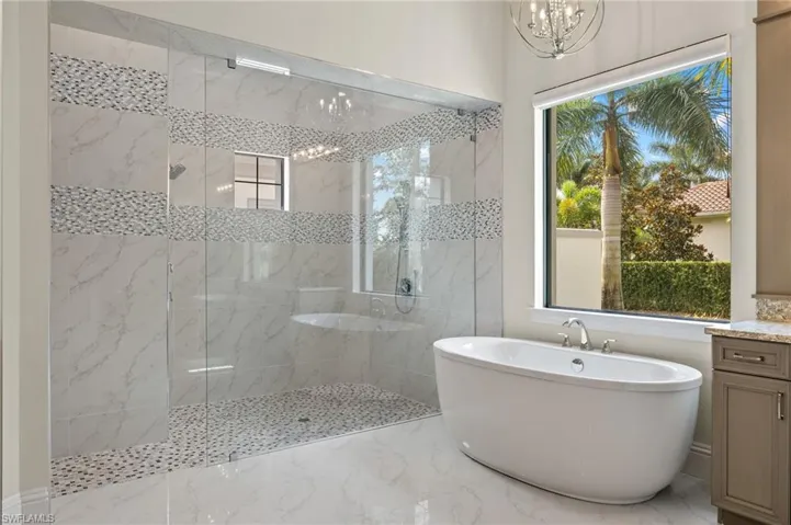 Bathroom featuring vanity, sunlight, and three shower head shower with separate bathtub