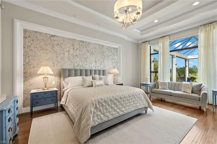 Bedroom featuring hardwood floors, a notable chandelier, crown molding, and a raised ceiling