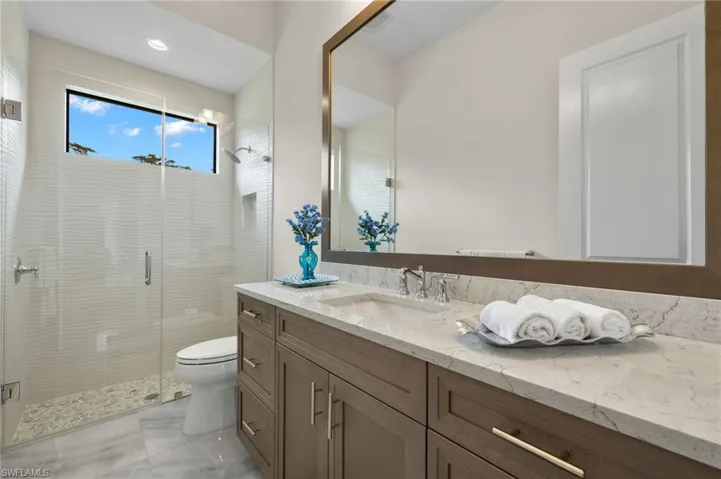 Bathroom featuring step down shower with frameless door