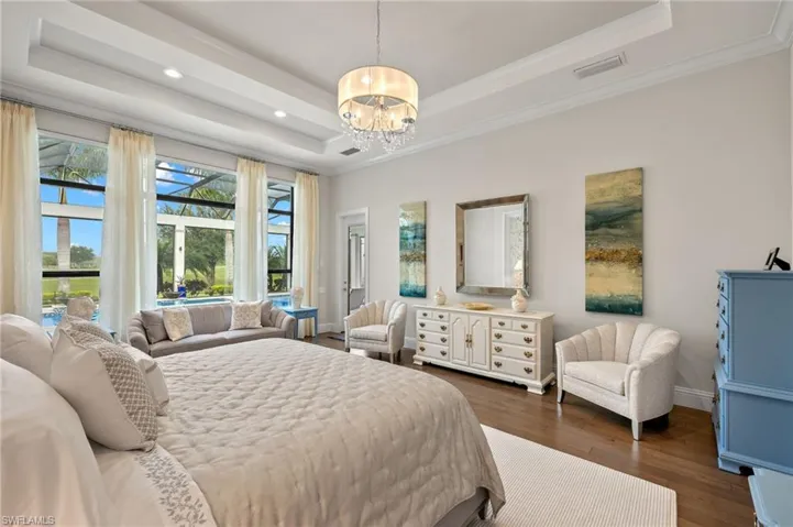 Bedroom with a chandelier, crown molding, hardwood style floors, and a tray ceiling