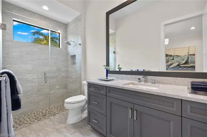 Bathroom featuring step down shower with frameless door