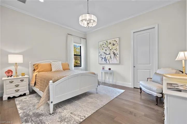 Bedroom featuring ornamental molding, hardwood style floors, and an inviting chandelier