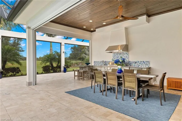 View of patio with gas grill, bar seating, sink and refrigerator