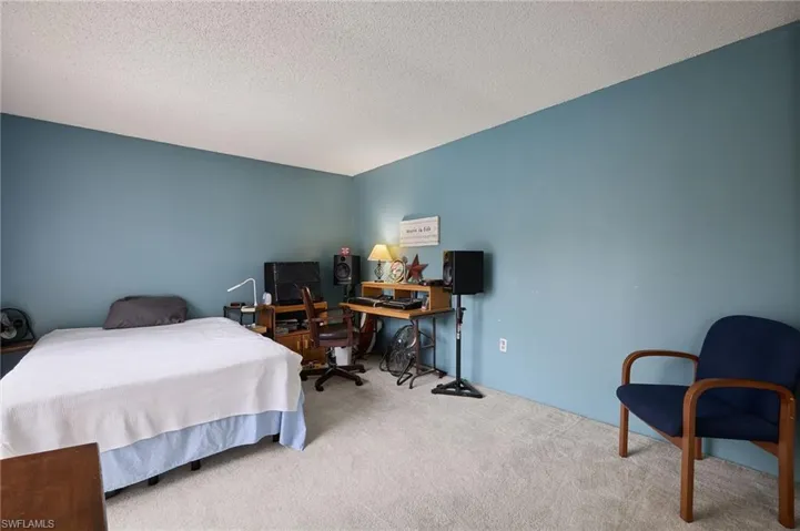 Carpeted bedroom with a textured ceiling and an office area