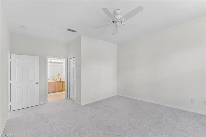 Unfurnished master bedroom with light colored carpet, ceiling fan, a closet, and connected bathroom