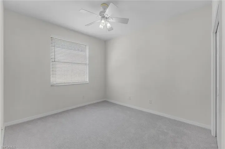 Empty room featuring light colored carpet and ceiling fan