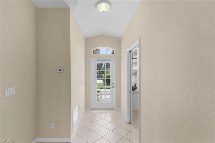 Doorway to outside with vaulted ceiling and light tile patterned floors