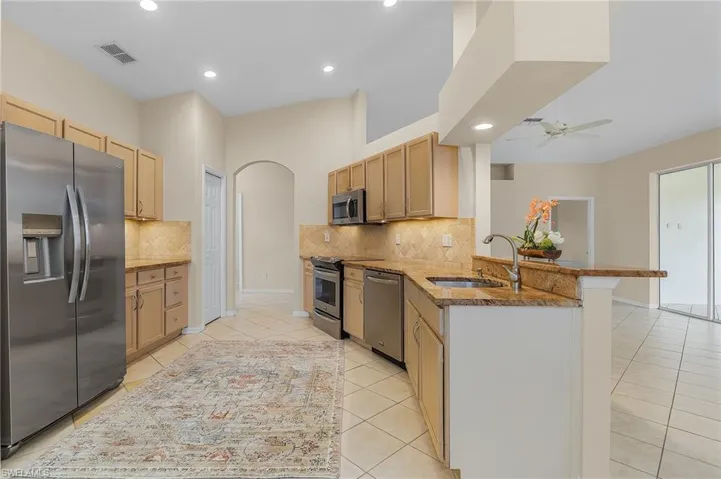 Kitchen with kitchen peninsula, sink, ceiling fan, decorative backsplash, and appliances with stainless steel finishes