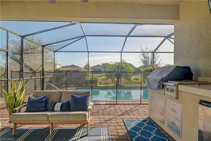 View of swimming pool featuring area for grilling, grilling area, glass enclosure, and a patio
