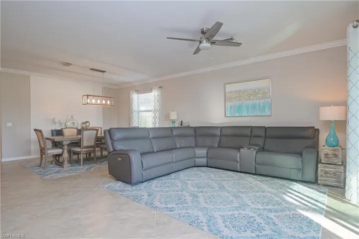 Tiled living room with ceiling fan and crown molding