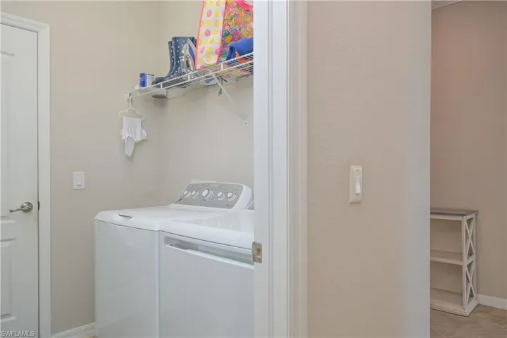 Clothes washing area featuring separate washer and dryer and light tile floors