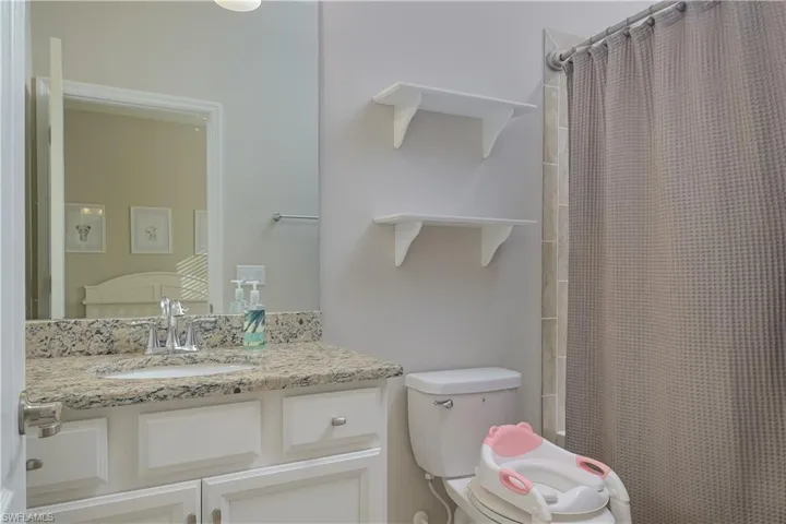 Bathroom with vanity with extensive cabinet space and toilet