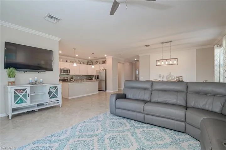 Tiled living room featuring sink, ornamental molding, and ceiling fan