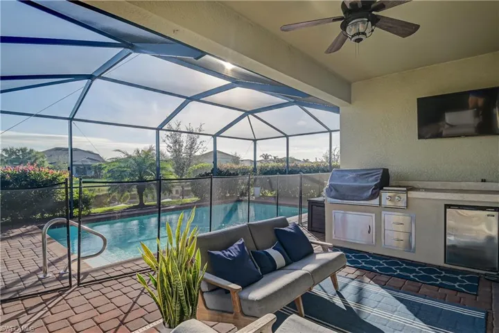 View of swimming pool featuring area for grilling, a patio, a lanai, and ceiling fan
