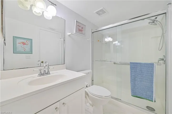 Bathroom with walk in shower, tile patterned floors, toilet, and vanity