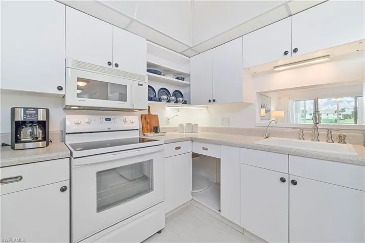 Kitchen with sink, white cabinetry, light tile patterned floors, and white appliances