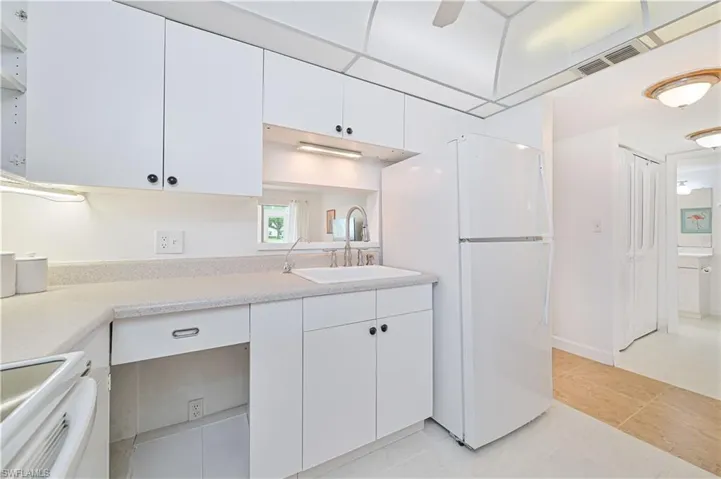 Kitchen featuring sink, white cabinets, white refrigerator, and light tile patterned floors