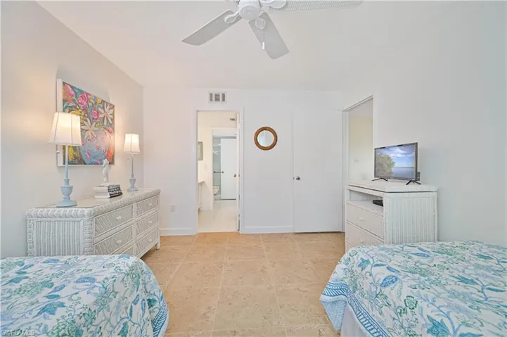 Bedroom with ensuite bathroom, light tile patterned floors, and ceiling fan