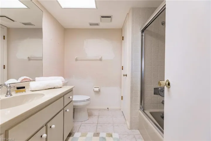 Full bathroom with tile patterned flooring, vanity, toilet, and enclosed tub / shower combo