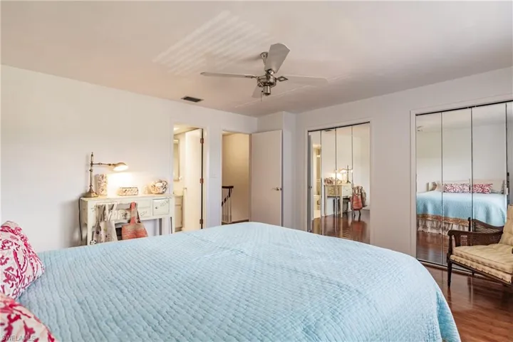 Bedroom with dark hardwood / wood-style flooring, two closets, and ceiling fan