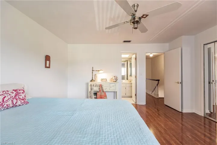 Bedroom with ensuite bathroom, ceiling fan, and dark wood-type flooring