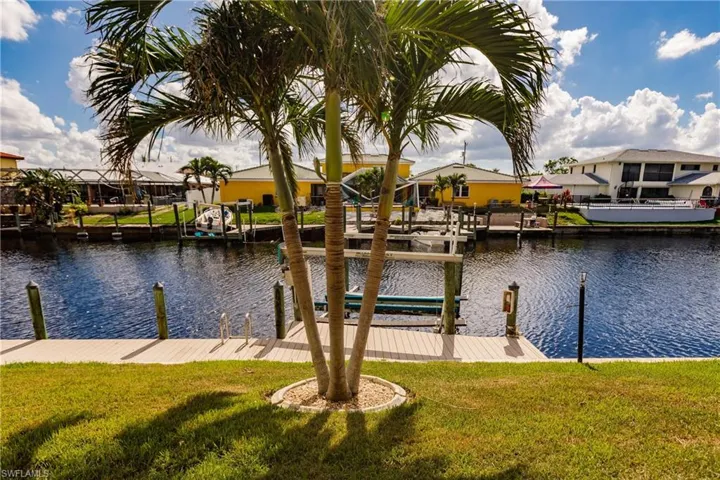 View of dock with a lawn and a water view