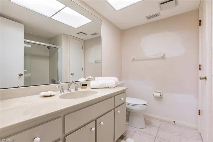 Bathroom featuring tile patterned flooring, vanity, toilet, and an enclosed shower