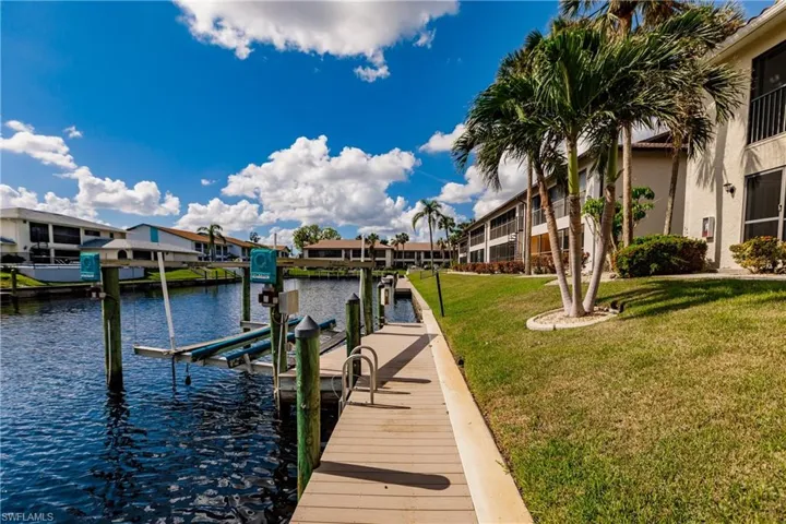 View of dock with a lawn and a water view
