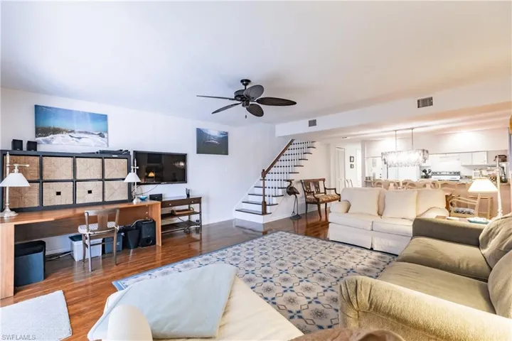 Living room with hardwood / wood-style flooring and ceiling fan with notable chandelier