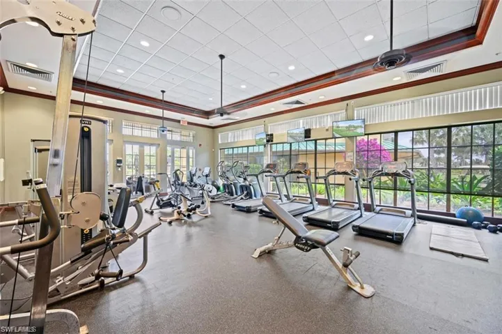 Fitness center featuring a drop ceiling with recessed lighting, crown molding, rubberized flooring, and expansive floor-to-ceiling windows