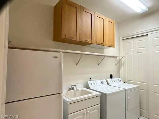 Washroom with washer and dryer and cabinet space and extra refrigerator