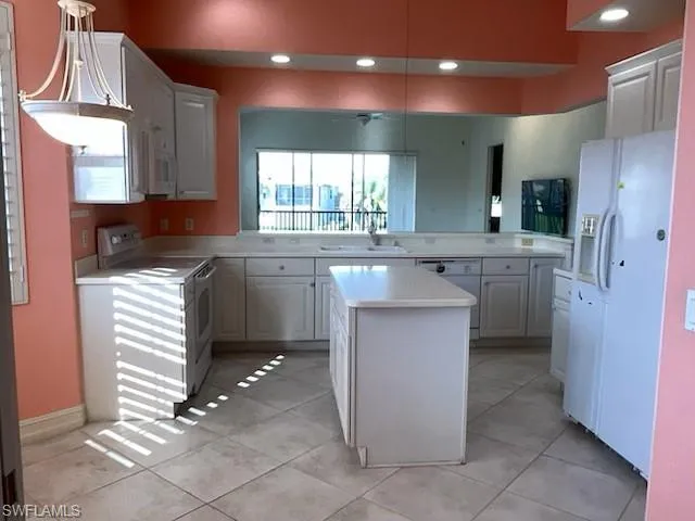 Kitchen with white appliances, light countertops, a center island, a ceiling fan
