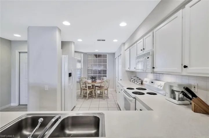 Kitchen with white appliances, white cabinetry, light countertops, recessed lighting, and light tile patterned floors