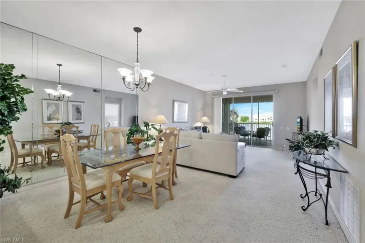 Carpeted dining room featuring ceiling fan, plenty of natural light, and a chandelier