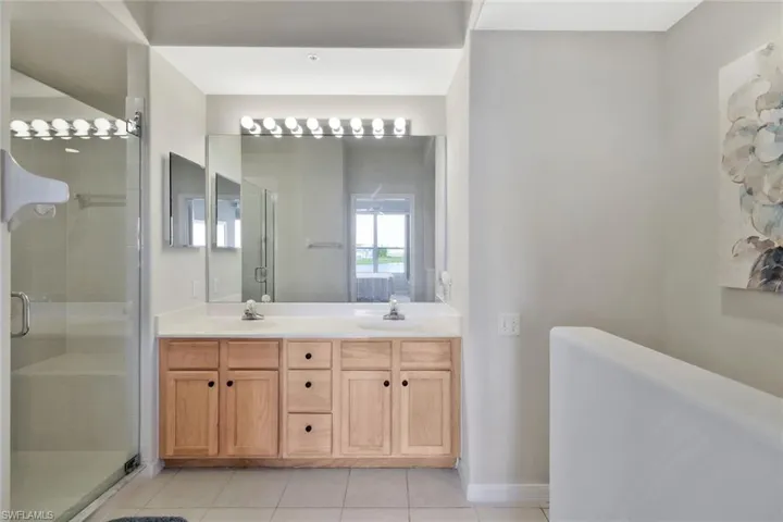 Full bath featuring double vanity, a stall shower, and light tile patterned flooring
