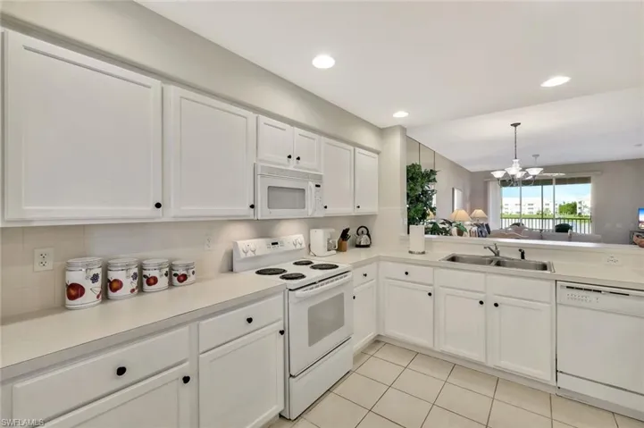 Kitchen with white appliances, pendant lighting, white cabinets, light countertops, and light tile patterned flooring