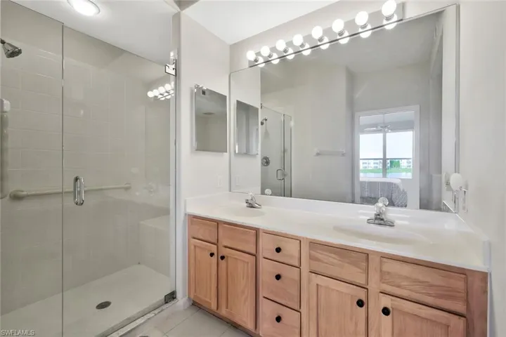 Full bathroom featuring ensuite bath, a stall shower, double vanity, light tile patterned floors, and a ceiling fan