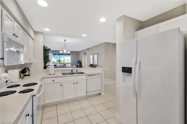 Kitchen featuring white appliances, white cabinetry, light countertops, and recessed lighting