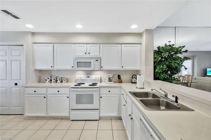 Kitchen with white appliances, white cabinetry, light countertops, light tile patterned floors, and recessed lighting
