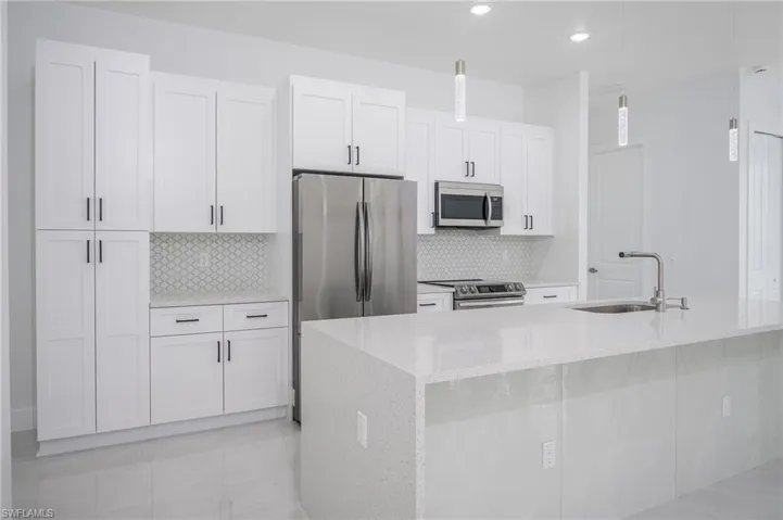 Kitchen with white cabinetry, light stone countertops, and backsplash