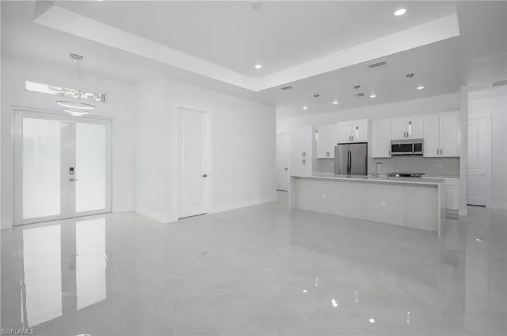 Kitchen with white cabinetry, a tray ceiling, stainless steel appliances, a spacious island, and open floor plan