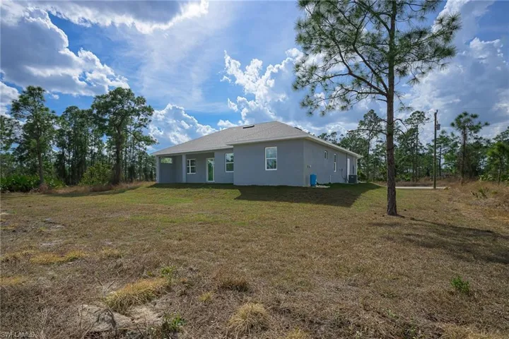 Back of house featuring stucco siding and a lawn