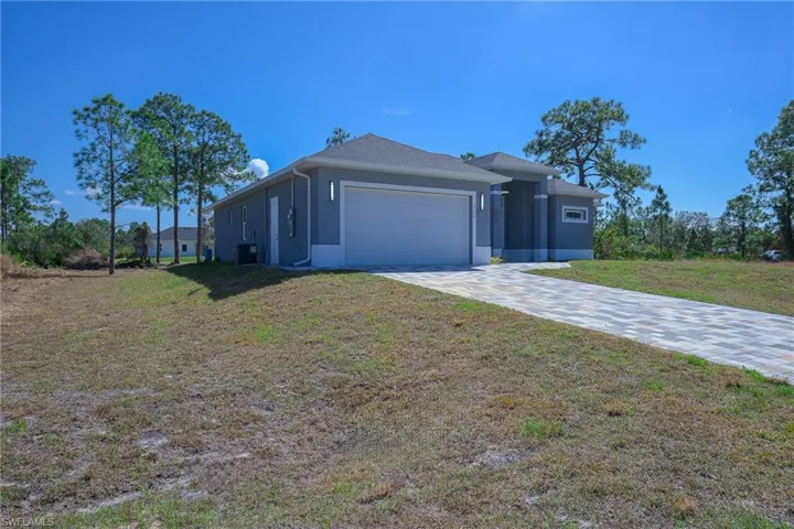 View of front facade with a front lawn, stucco siding, driveway, and an attached garage